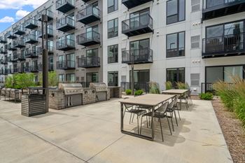 a patio with tables and chairs in front of an apartment building
